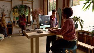 Two people in an office working on an Apple iMac M4