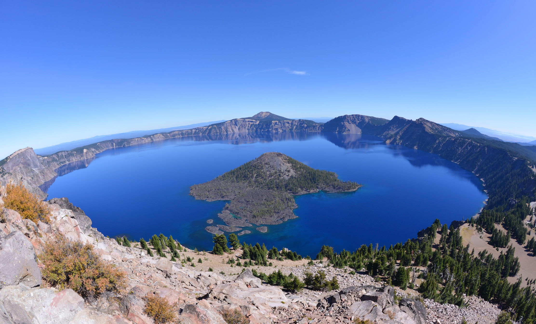 Wide-angle view of Crater Lake, which is a lake of deep blue water filling a collapsed volcanic caldera