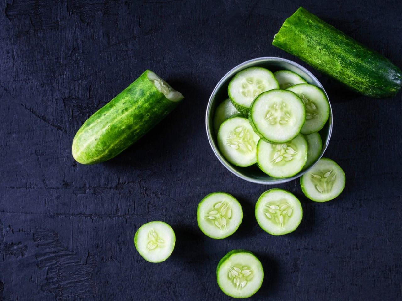 Bowl Of Sliced Cucumber Next To Cut In Half Cucumber