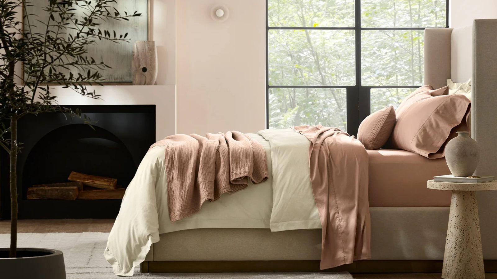 Pale pink bedroom with Crittall windows and a bed with terracotta bedsheets, a white comforter and a terracotta blanket