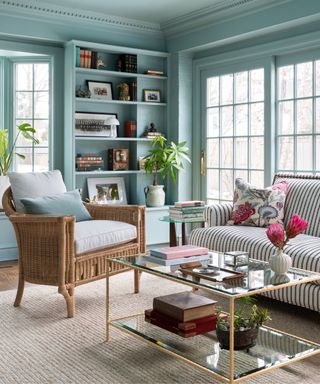 blue living room sun room with a striped sofa and rattan accessories and a decorative shelving built in