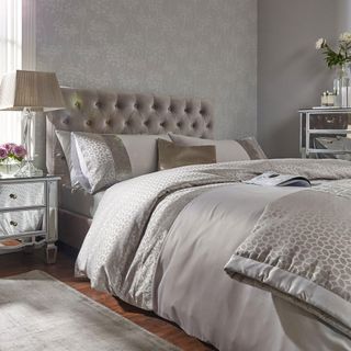 grey themed bedroom with wallpaper and wooden flooring