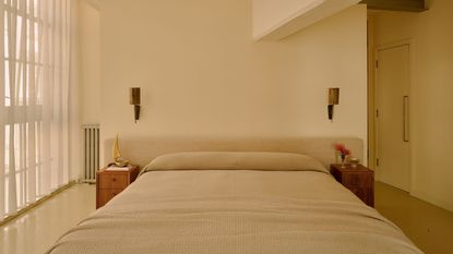Image of a color drenched, beige/butter yellow bedroom with relaxed bedding and linen curtains on the windows.