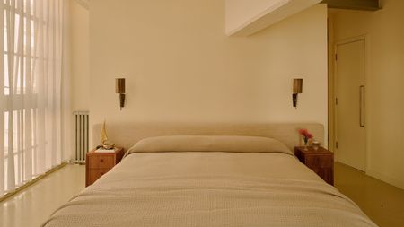 Image of a color drenched, beige/butter yellow bedroom with relaxed bedding and linen curtains on the windows.