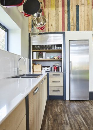 A wood kitchen with a kitchen larder with shutter to cover it