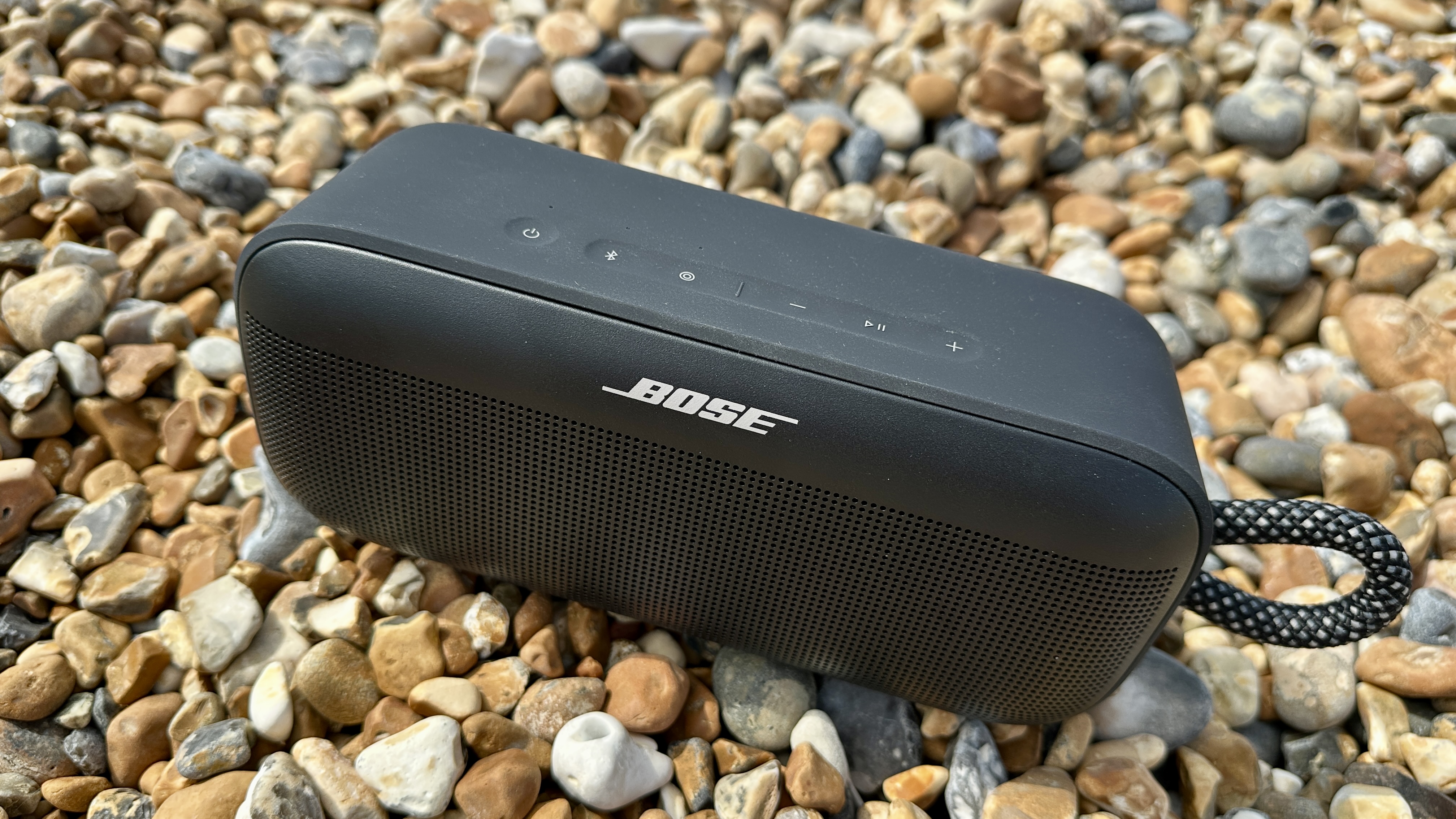 Bose SoundLink Plus on Brighton Beach pebbles, with the old pier in the background