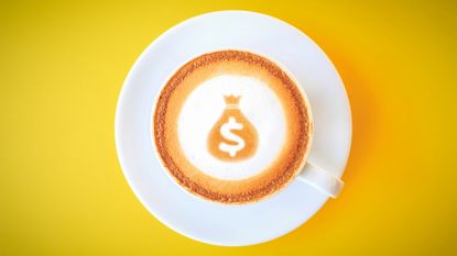 Top view of a coffee cup and latte art showing a money sack with dollar sign