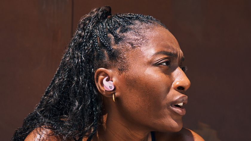  The Powerbeats Fit in pink in a woman&#039;s ear. She looks out of breath, in the middle of a workout