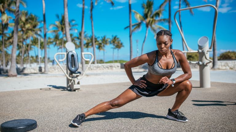 Athletic women doing side lunges on a sea front