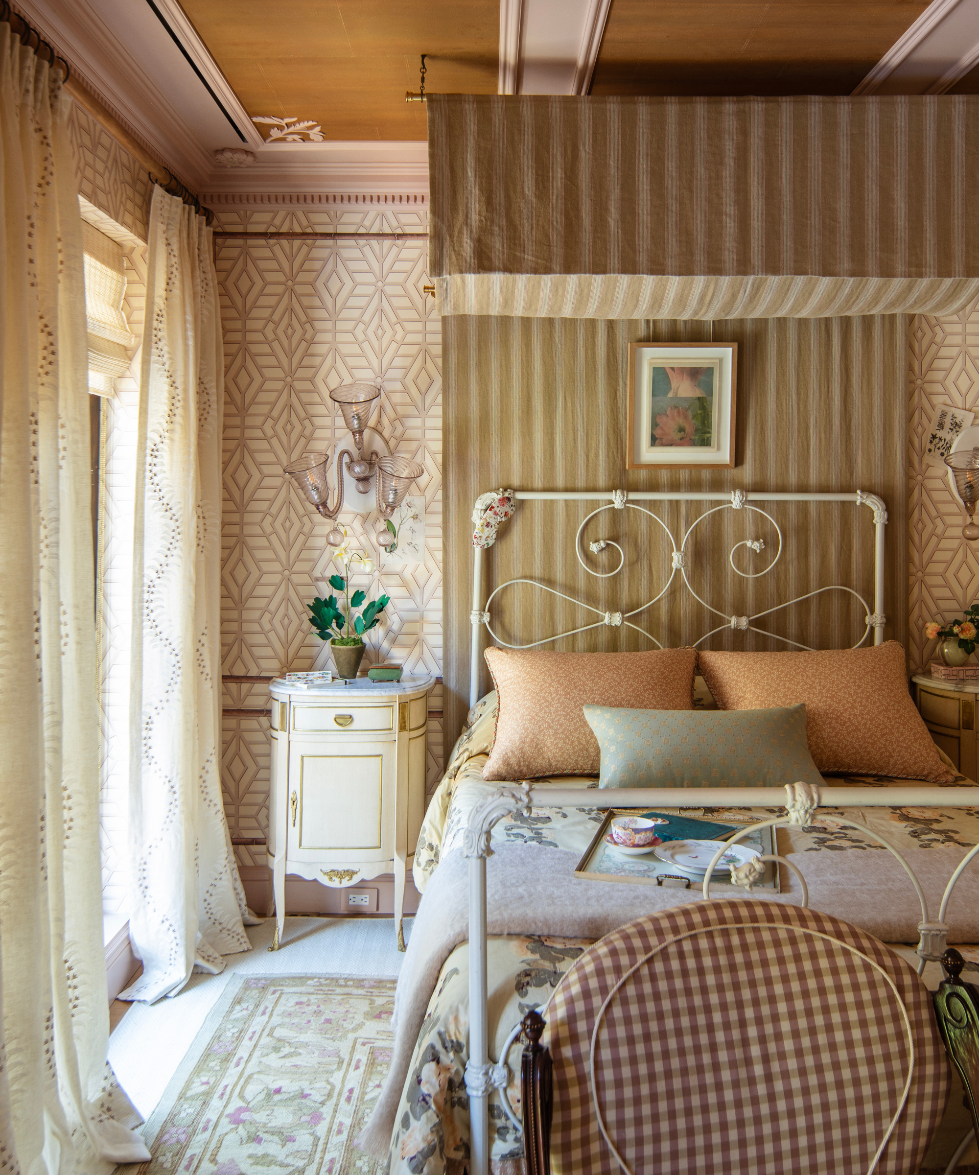 Whimsical, antique-inspired NYC bedroom featuring a layered mix of light pastel throw pillows and vintage floral bed blankets.