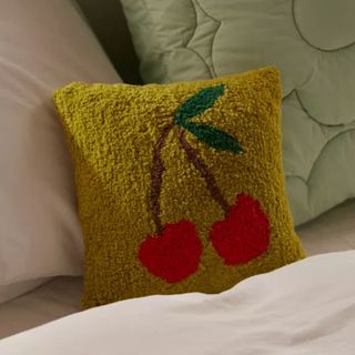 A Cherries Tufted Mini Throw Pillow on a sofa