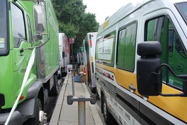 The team trucks are double parked on the city street.
