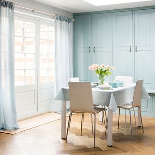 dining area with wooden floor with white french patio door and blue cabinet with white tables and chairs