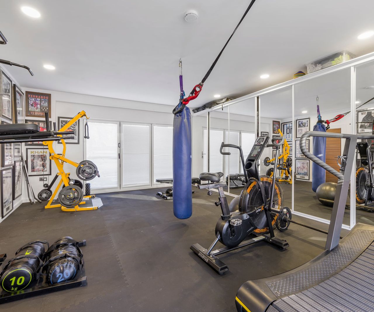A home gym with mirrored walls with a punch bag in the middle of the room