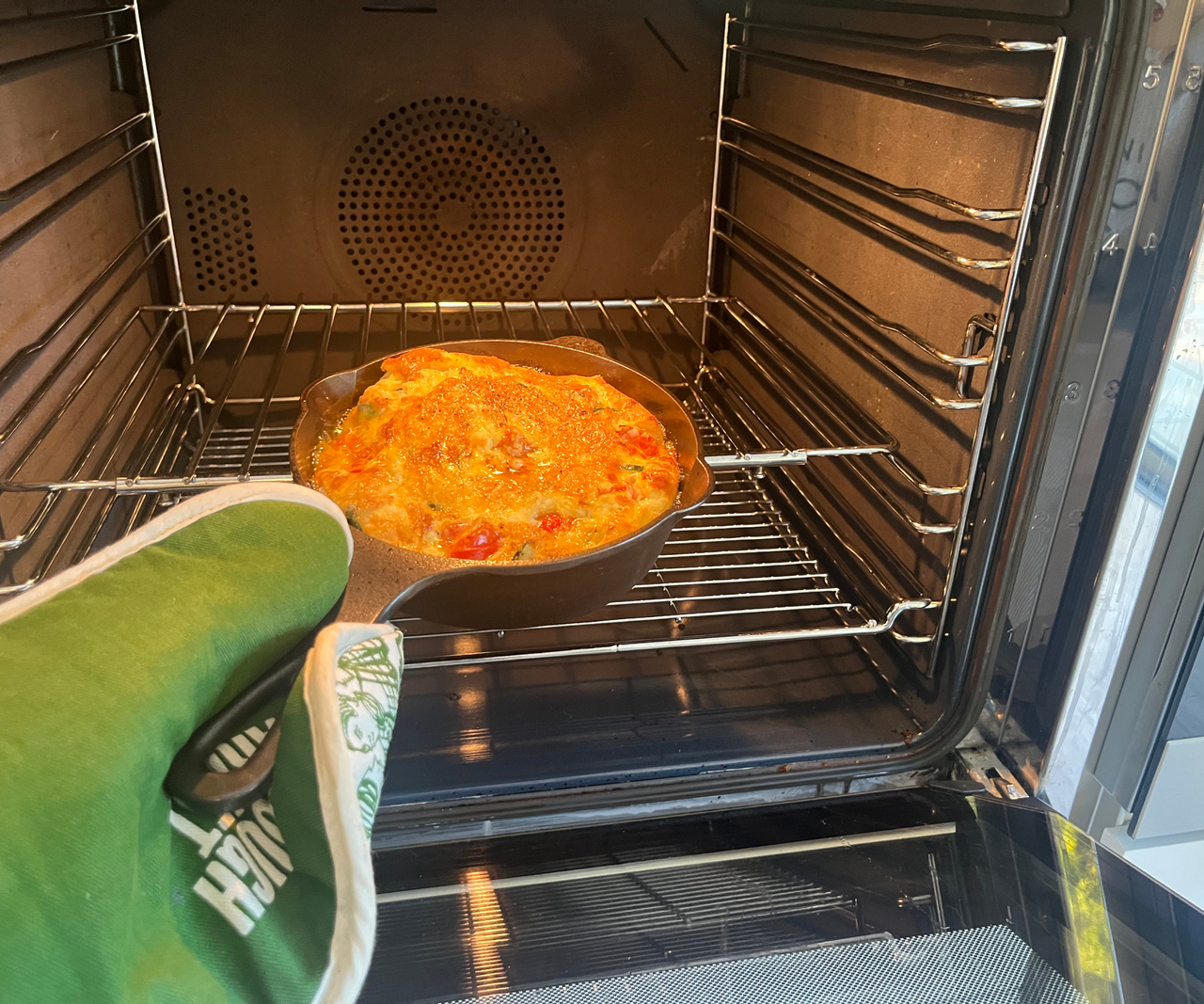 Lancaster Cast Iron Skillet being removed from an oven, filled with a cooked frittata.