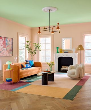 colorful living room with light green ceiling, pink walls and multicolored rug