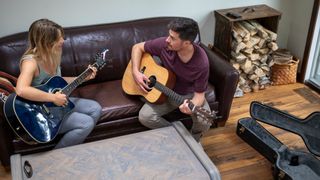 Man and women having a guitar lesson with two acoustic guitars