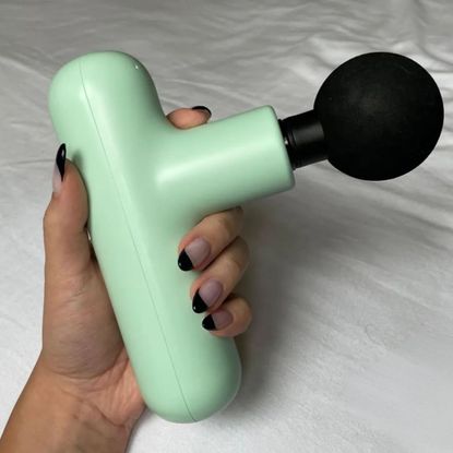 Valeza holding one of the best massage guns tested by Marie Claire UK