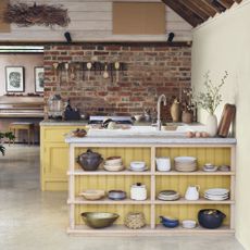 yellow kitchen in barn conversion with brick wall behind