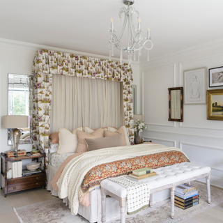 Cozy bedroom with large double bed against white interior wall. Blankets and bedspreads in organge, cream and beige are lost