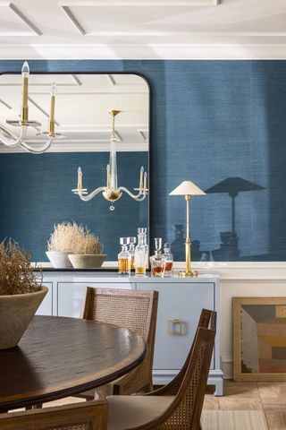 dining room with dark polished wood table and blue textured wallcovering large mirror and chandelier
