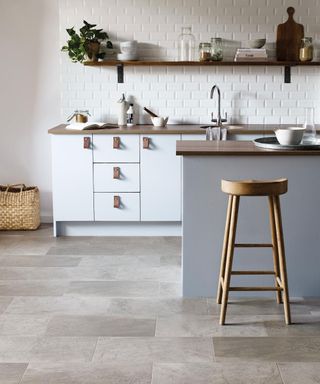 natural stone look vinyl tiles in a white kitchen with island. Flooring: Mineral in Broken Bond Laying Pattern by Amtico