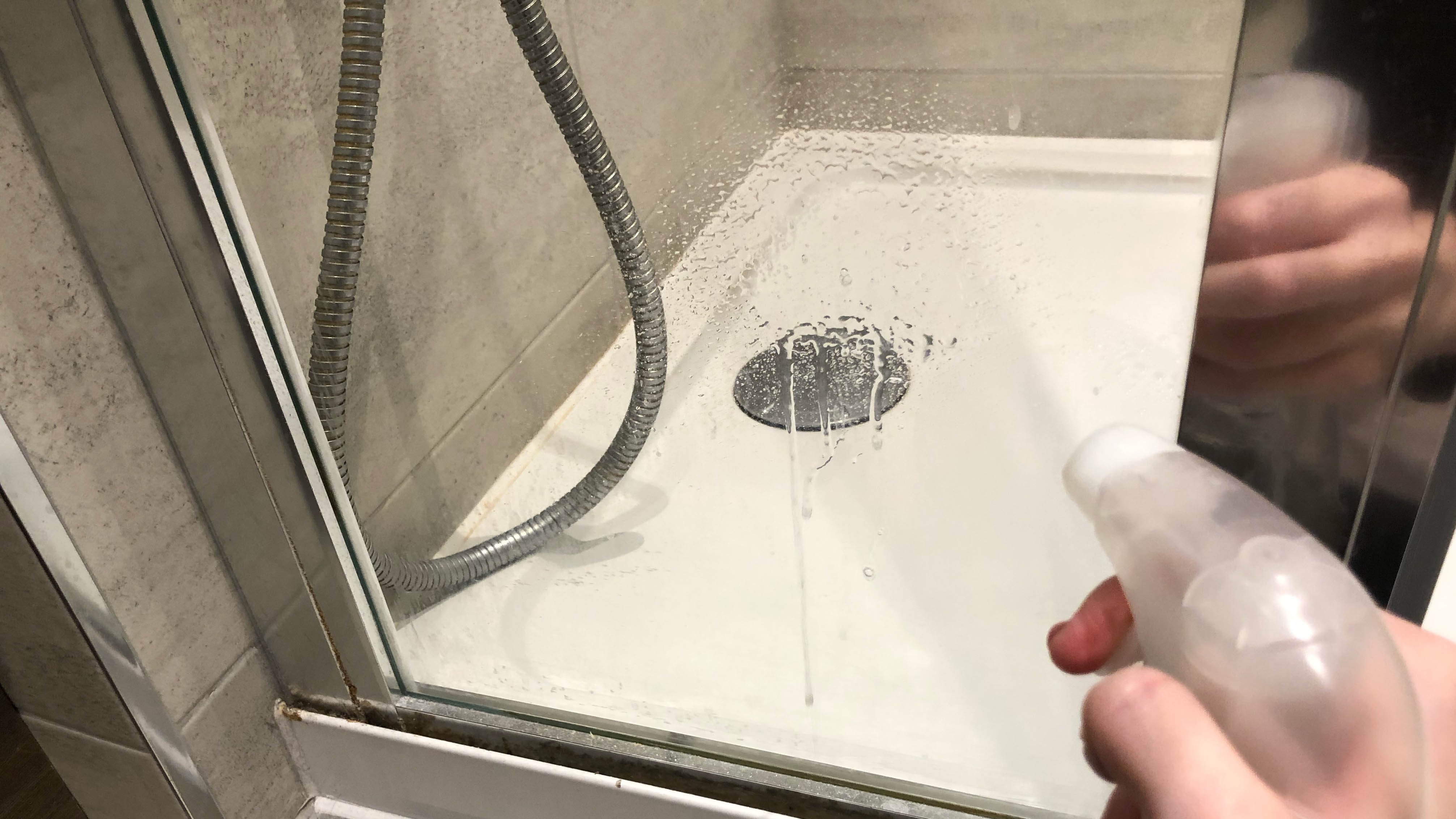 Someone sprays vinegar water on the shower glass panel