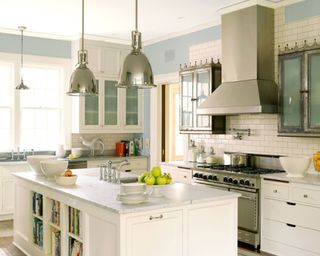 kitchen with white cabinets, white kitchen island with silver pair of pendant lights, light blue paintwork on walls