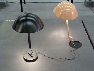 Two mushroom head shaped table lamps in black and beige, photograph on a grey surface