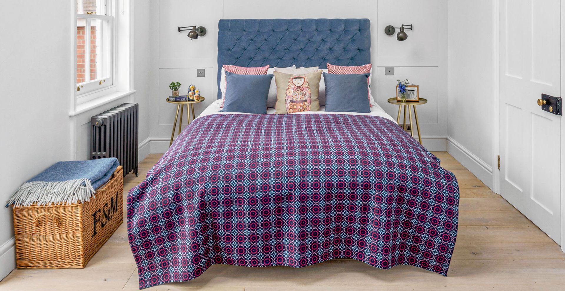 Pale gray bedroom with blue upholstered bed with blue bedding