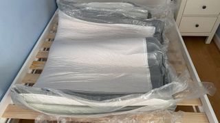 The Hypnia Supreme Memory Mattress in its plastic wrap on a bed