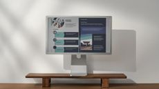 BOOX Mira Pro Color Version monitor, an electronic ink display showing a colour brochure. The monitor has a silvery finish and is pictured on a wooden desk in front of a white wall.