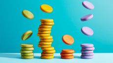 Tech spending concept image showing multi-colored coins raining down from above and stacking on top of each other. 