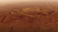 a rusty red landscape shows a smattering of craters from a high altitude.