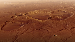 a rusty red landscape shows a smattering of craters from a high altitude.