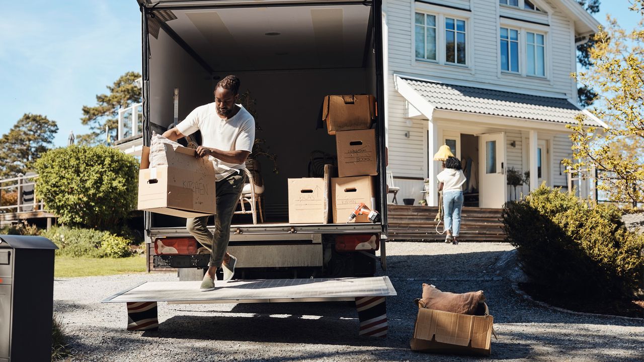 Man unloading cardboard boxes from van.