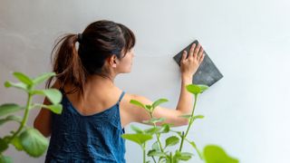 woman sanding wall