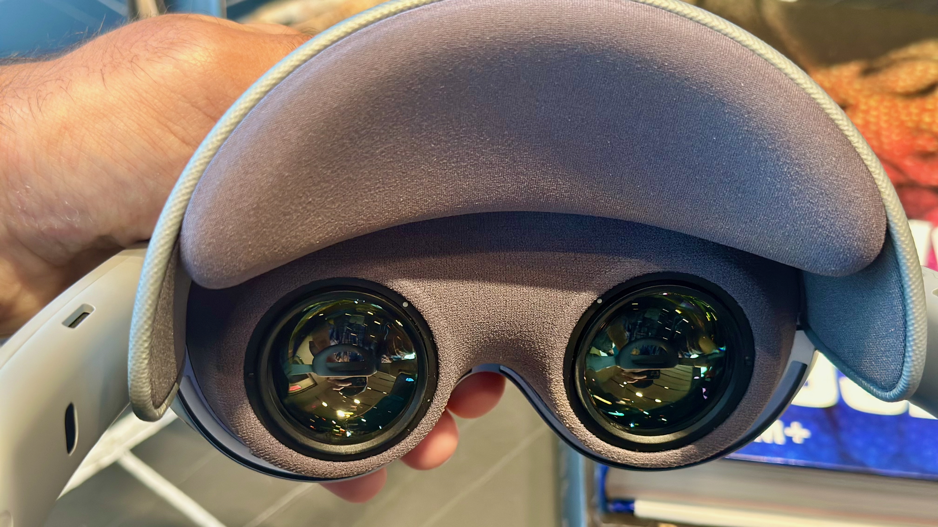 A close-up photo of the Samsung Galaxy XR headset held in hand, pointed toward the lenses.