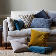 white sofa with designed cushions and grey wall