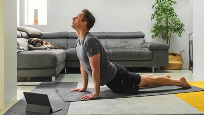 Man practices yoga on a yoga mat at home