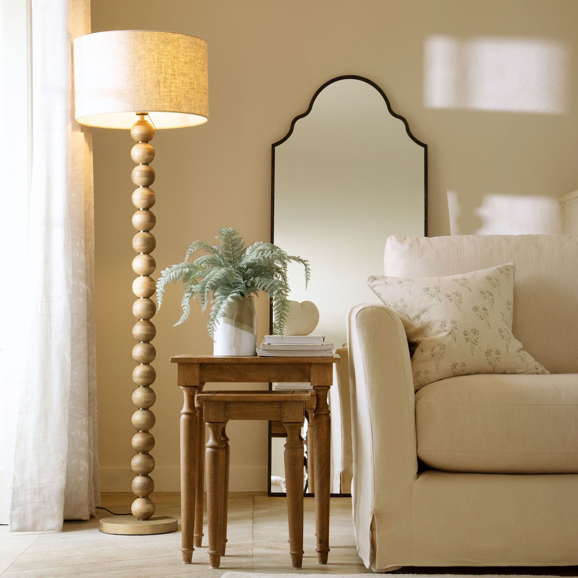neutral living room with a sofa and wooden bobble based floor lamp with a neutral drum shade