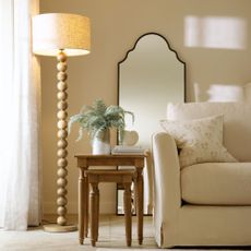 neutral living room with a sofa and wooden bobble based floor lamp with a neutral drum shade