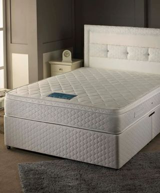 The Sheraton Mattress on a white bed base against cream walls. 