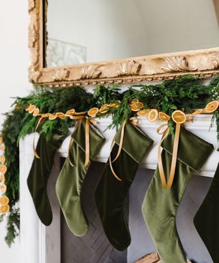 green velvet stockings hanging on a fireplace with dried oranges