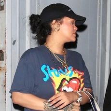 Rihanna wears a graphic T-shirt and sneakers and carries a tote bag