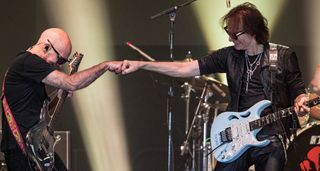 Joe Satriani [left] fistbumps Steve Vai onstage as the pair perform together onstage with their Ibanez signature guitars