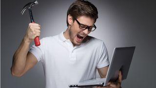 Un homme en colère frappe son ordinateur portable avec un marteau