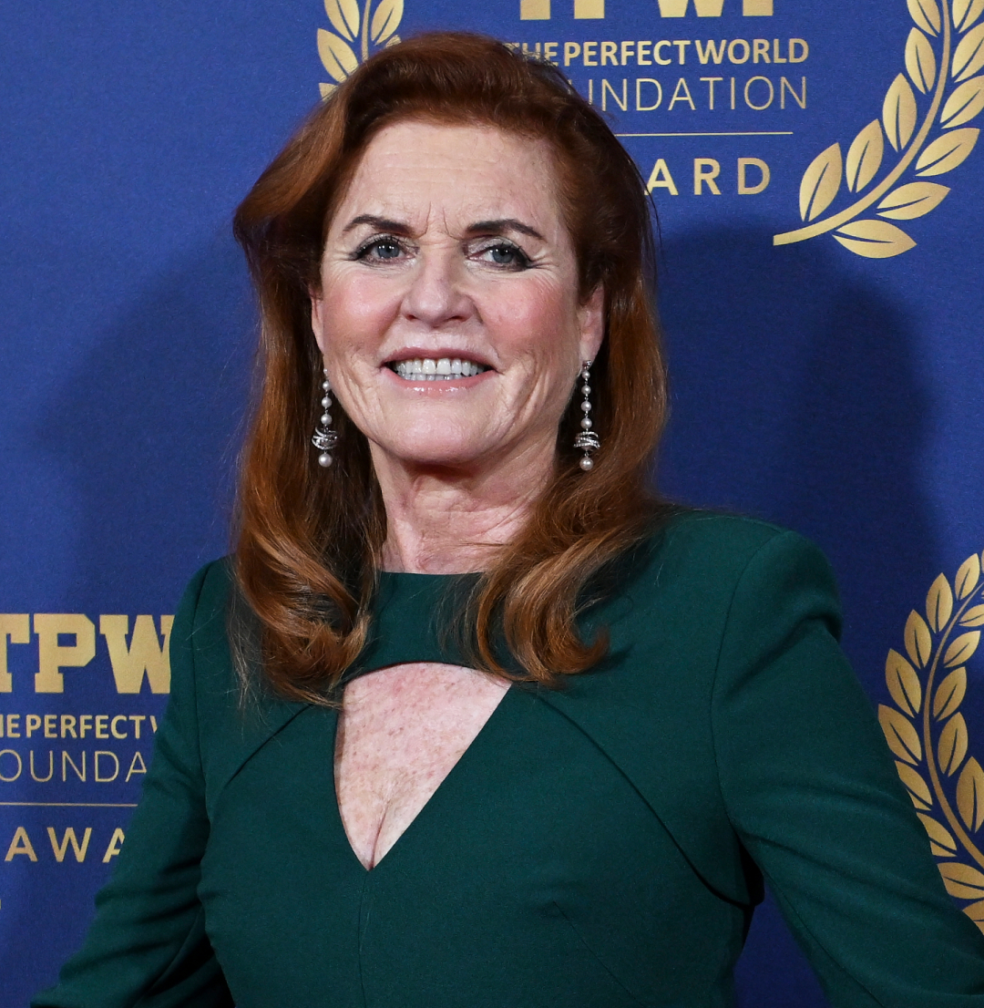 Sarah Ferguson wearing a green gown posing in front of a blue step and repeat