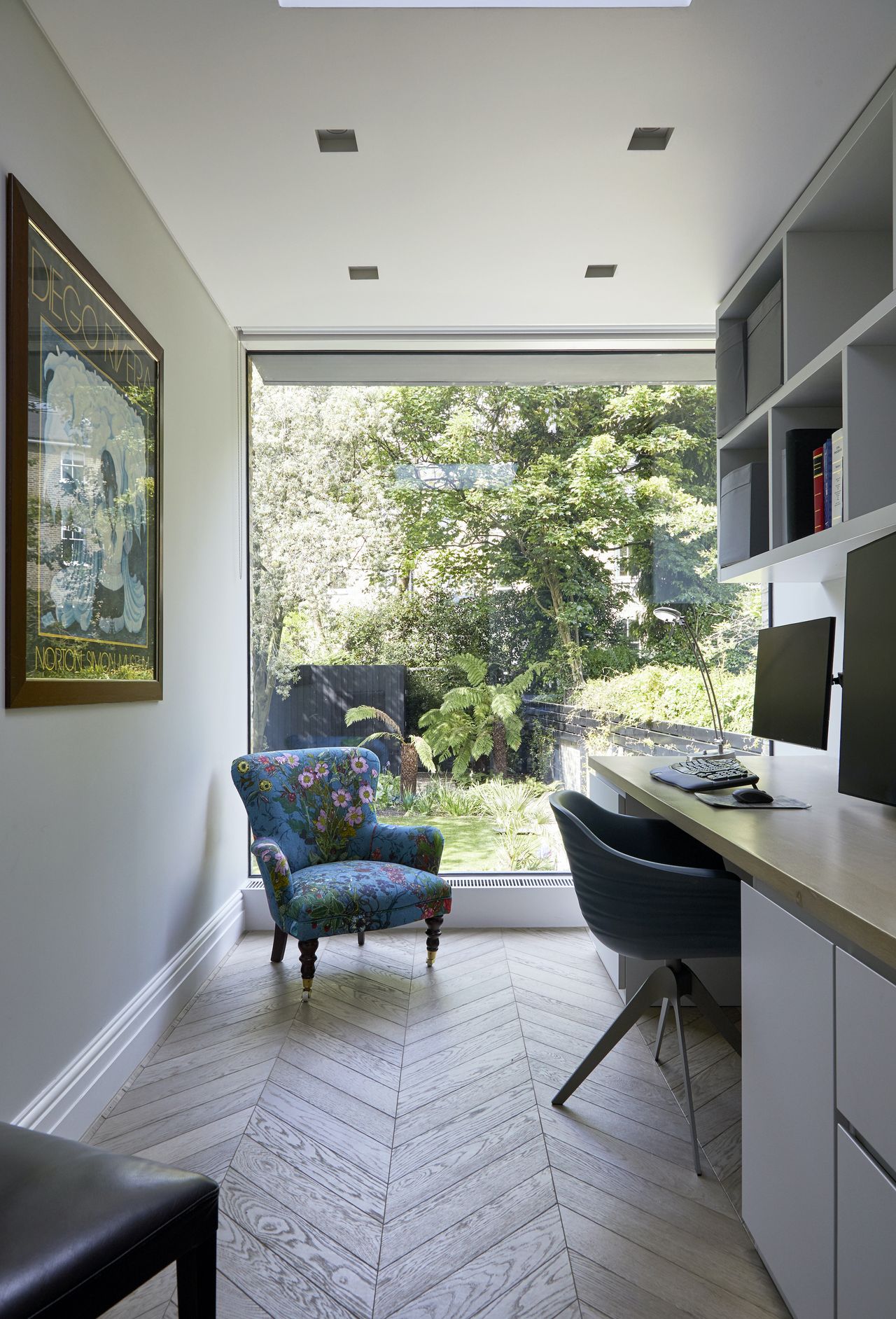 Home office with picture window, monitors, and wall-mounted chair