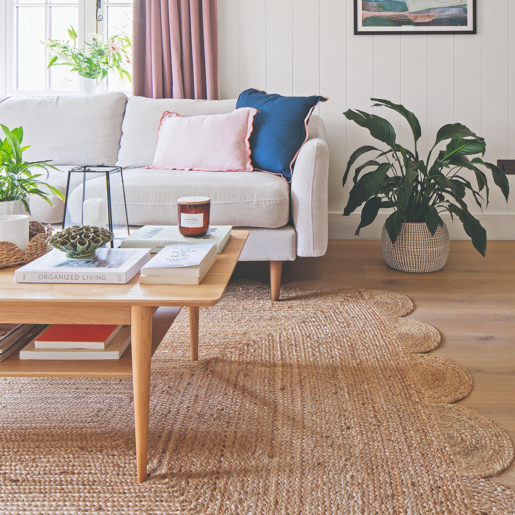 A living room with a grey sofa with tapered wooden legs and a scalloped-edge jute rug underneath
